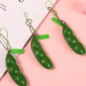 Grüner Edamame-Zappel-Schlüsselanhänger zum Stressabbau auf einem rosa Hintergrund