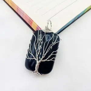 Detailed view of a handmade wire-wrapped tree of life pendant with a black gemstone base.