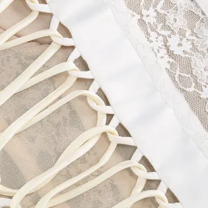 Dettaglio raffinato di pizzo bianco e intricata allacciatura a lisca su abito in rete mesh