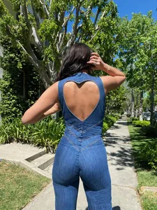 Back view of a retro denim jumpsuit featuring a unique heart-shaped cutout detail outdoors.