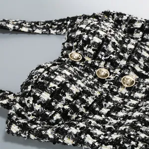 Primer plano de un vestido de tweed blanco y negro con lentejuelas y botones dorados