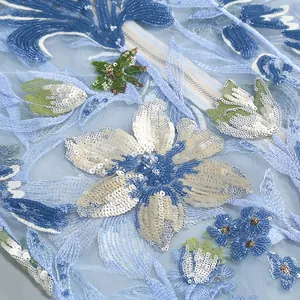 Gros plan de broderies florales bleues et paillettes sur tissu de robe de soirée