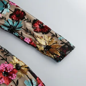 Detailopname van levendig veelkleurig pailletten bloemendessin op een mesh mouw detail