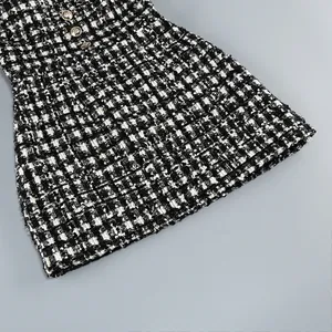 Primer plano de vestido de tweed a cuadros blanco y negro con lentejuelas y textura.