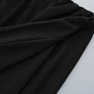 Macro view of black pleated fabric showing the fine knit texture and material details.
