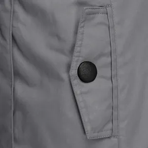 Macro detail of a gray winter jacket featuring a pocket flap with a black button.