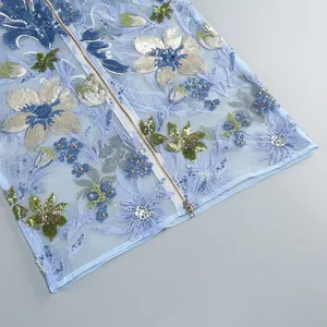 Détail d'une robe de soirée bleu clair avec broderie florale complexe et paillettes.