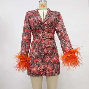 Detail view of V-neck floral dress with vibrant orange feather cuffs and belt