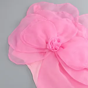 Detailed close-up of multilayered chiffon floral decoration on a pink party dress