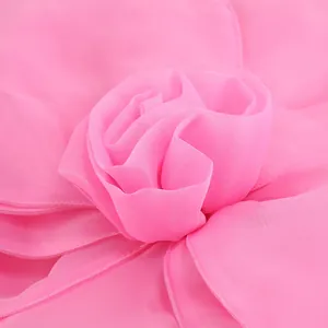 Detailed macro shot of the elegant pink chiffon rose flower decoration on the dress.