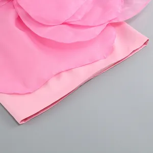 Close-up detail showing the exquisite layered pink petal decorations on a party dress