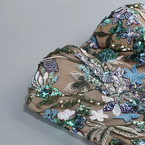 Détail macro montrant la broderie florale complexe et les paillettes étincelantes sur la robe
