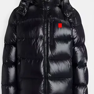 Detalle de una chaqueta acolchada negra brillante para hombre con capucha y etiqueta roja.