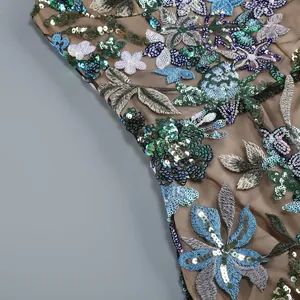 Gros plan sur les broderies florales et les paillettes d'une robe de soirée de luxe.