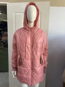 Primo piano di un piumino rosa media lunghezza con cappuccio e motivi geometrici trapuntati