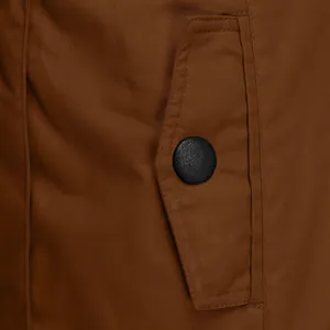 Macro view showing the fabric texture and pocket button of a brown winter coat.