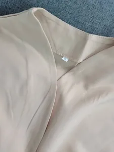 Close-up detail of the beige sleeveless jumpsuit neckline featuring a visible XL size tag