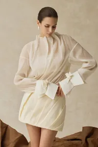 Detailansicht der transparenten Plissee-Bluse und des Kleider-Sets mit floralen Manschetten