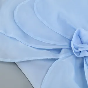Close-up detail of light blue chiffon dress with exquisite layered ruffles and floral accent