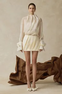 Elegantes dreiteiliges Set mit transparenter Rüschenbluse, Bustier und Faltenrock.