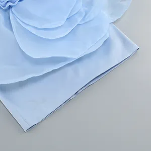 Detailed macro view of elegant layered fabric flower petals on a light blue party dress.