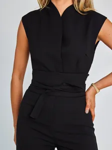Close-up detail of a chic black sleeveless jumpsuit featuring a belted waistline