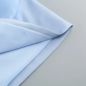 Close-up macro view showing the light blue fabric texture and stitching of the gown