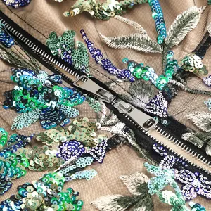 Gros plan d'une robe de soirée avec broderies de paillettes florales et fermeture éclair.
