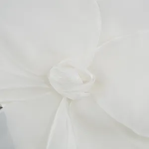 Close-up detail of elegant white organza flower decoration on evening party dress
