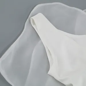 Close-up detail of a white off-shoulder evening dress with elegant sheer mesh layering