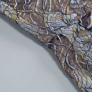 Close-up macro view of the intricate blue and gold floral lace texture on a fishtail dress