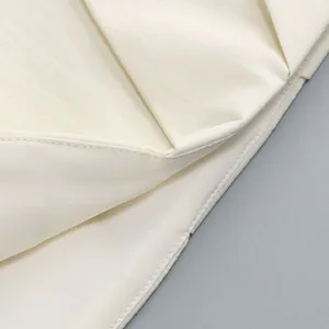 Detailansicht des zarten cremefarbenen Faltenstoffs und der hochwertigen Nähte am Kleid