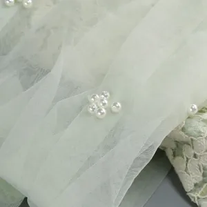 Close-up of elegant sage green tulle and lace dress with delicate pearl beads