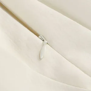 Detail-Nahaufnahme des unsichtbaren Reißverschlusses an einem cremefarbenen Kleid.