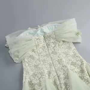 Detail of light green lace dress with off-the-shoulder pleated mesh sleeves and 3D pearls.