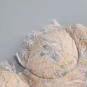Detailed view of intricate floral lace and delicate eyelash trim on a peach bustier dress