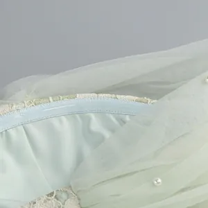 Close-up view showing the intricate pearl beads and lace detail on a mint green tulle dress