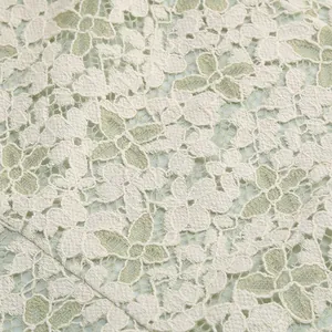 Close-up of delicate floral ivory lace fabric with pale green mesh lining for fairy dress.