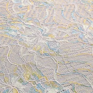 Close-up detail of intricate floral lace fabric with blue and yellow hues