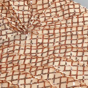 Dettaglio macro di paillettes oro rosa e argento su tessuto a rete beige per abiti da festa