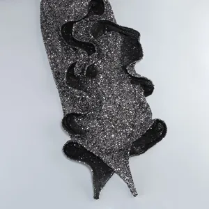 Detailed view of a black shimmering sequin dress featuring an elegant ruffled hem design
