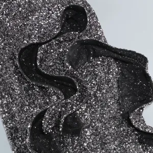 Close-up detail of shimmering silver sequins and elegant ruffle hem on a party dress.