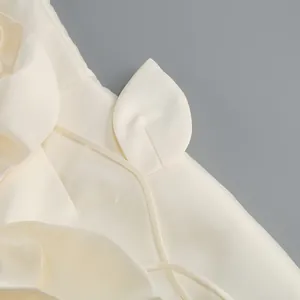 Gros plan sur l'élégante fleur en satin crème et le détail de laçage délicat de la robe