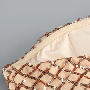 Dettaglio ravvicinato delle paillettes oro champagne con motivo a rombi sull'abito.