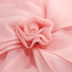 Macro detail view of a pink handmade 3D fabric flower decoration on an elegant party dress