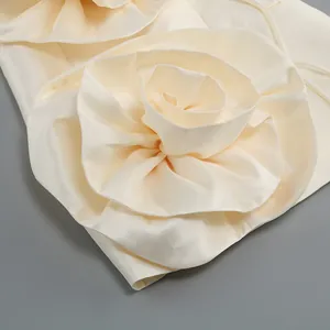 Vue détaillée de la fleur en tissu sur une robe en satin ivoire, texture élégante.