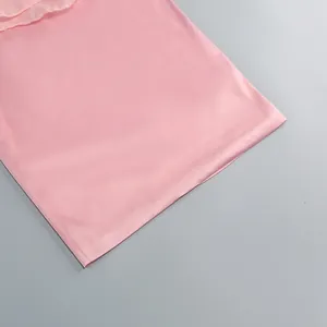 Detail view of the smooth pink satin fabric and clean hem of a stylish party dress.