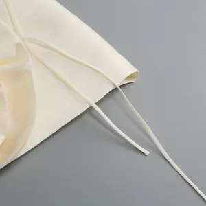 Gros plan d'une robe en satin crème montrant les détails des fines bretelles à nouer