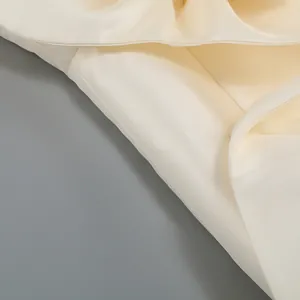 Vue détaillée montrant la texture lisse du tissu en satin blanc cassé d'une robe
