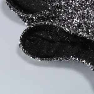 Detailed close-up view of silver sequins on black fabric for elegant evening party dress